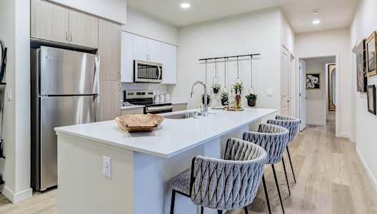 an open kitchen with a large island with four chairs