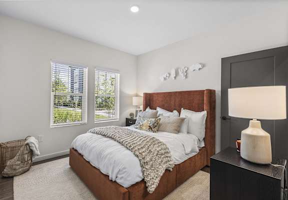 A bedroom with a large bed and a lamp on a side table.