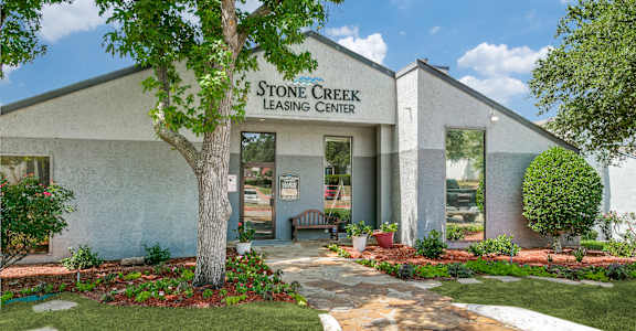 Stone Creek Leasing Center is a building with a tree in front.