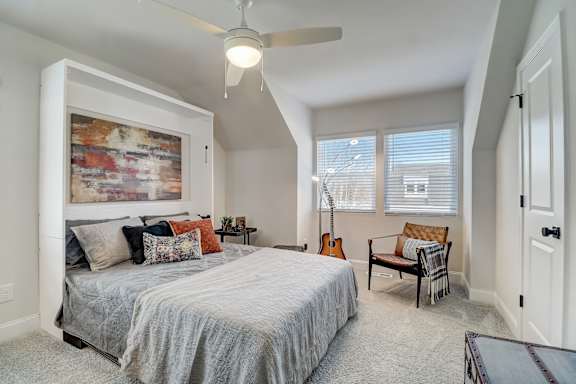 A bedroom with a bed, a chair, and a guitar.