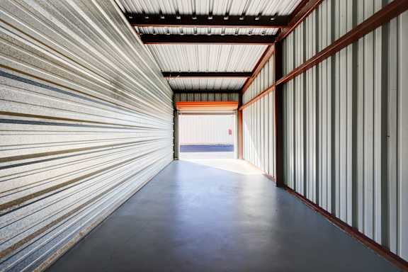 A long, narrow corridor with a metallic wall on one side and a white wall on the other.