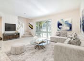 Thumbnail 7 of 22 - A modern living room with a glass coffee table and a white couch.