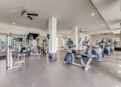Thumbnail 4 of 19 - a gym with cardio machines and a ceiling fan