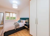 Thumbnail 1 of 5 - a bedroom with a bed and white cabinets