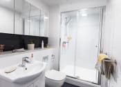 Thumbnail 6 of 8 - a bathroom with a white sink and toilet next to a shower with a glass door