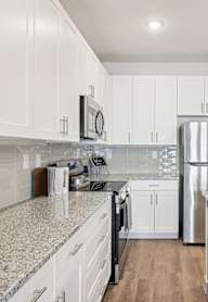 A kitchen with white cabinets and a granite countertop.