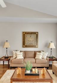 A living room with a couch, two chairs, a coffee table, and a painting on the wall.