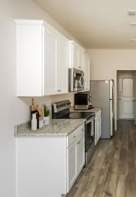 a kitchen with white cabinets and marble counter tops