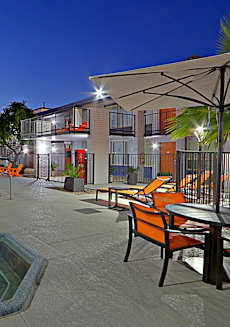 A swimming pool area with orange chairs and a table at Allora Phoenix Apartments, Arizona