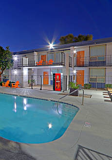 A swimming pool surrounded by orange chairs and a building in the background.