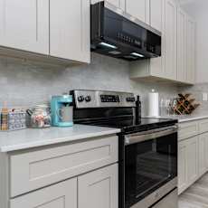 a kitchen with stainless steel appliances and white cabinets at Mihir Taylor, Texas
