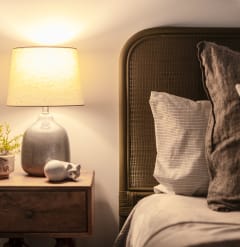 a bedroom with a bed and a lamp and a night stand with a vase