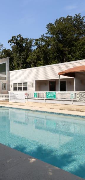 a swimming pool in front of a white house with a palm tree