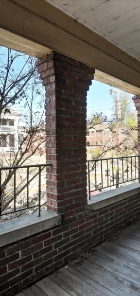 the porch of a brick apartment building with a wooden deck