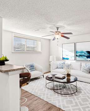 A living room with a white couch, a coffee table, and a ceiling fan.