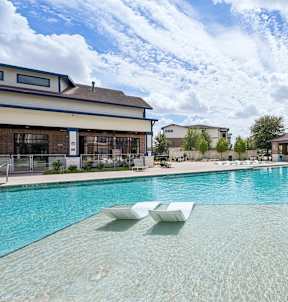 A large swimming pool with white sun loungers and a building in the background.