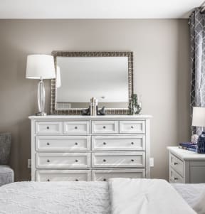 a bedroom with a large white dresser with a mirror on top of it