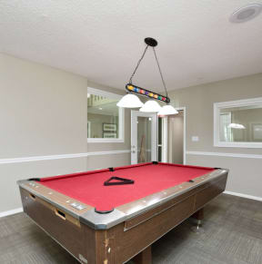a red pool table in a game room with a ceiling light
