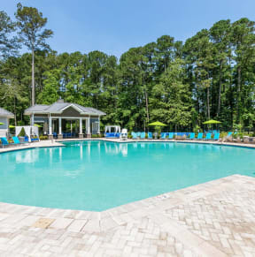 a resort style swimming pool with lounge chairs and umbrellas
