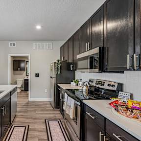 A modern kitchen with dark wood cabinets and a white countertop.