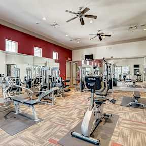 A gym with a variety of equipment including treadmills, weights, and exercise machines.
