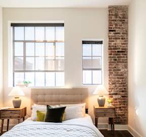 A bedroom with a brick wall and a large bed.