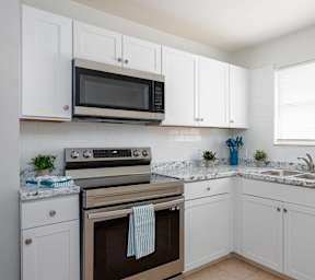 an empty kitchen with white cabinets and a stove and microwave