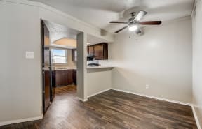 a bedroom with a ceiling fan and a kitchen in the background