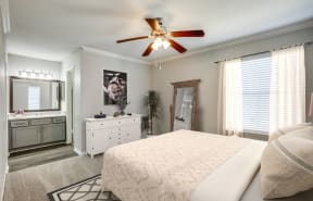 the master bedroom has a comfy bed and a ceiling fan