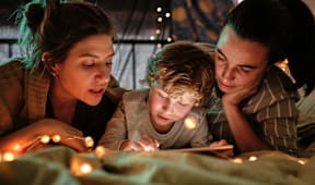 a boy and two women reading a book with lights