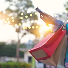 a woman holding shopping bags and looking at her cell phone