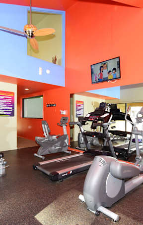 A gym with orange walls and a variety of exercise equipment.