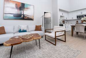 A modern living room with a white couch, a coffee table, and a painting on the wall.