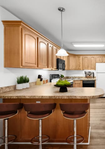 a kitchen with wooden cabinets and a large island with three stools