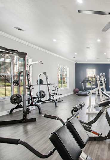 a gym with weights and cardio machines and a ceiling fan