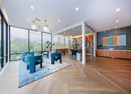 An apartment business lounge with a view of the trees outside the large windows.