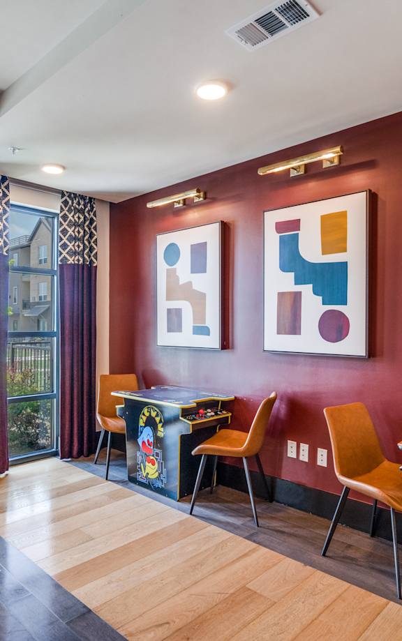 a game room with a pool table and chairs and paintings on the wall