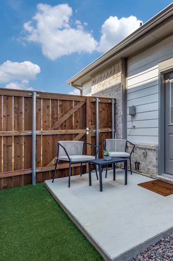 A patio with a table and chairs is surrounded by a wooden fence.