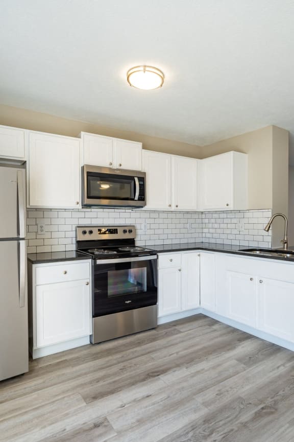 a kitchen with white cabinets and black appliances at Traditions at Slate Ridge, Ohio, 43068