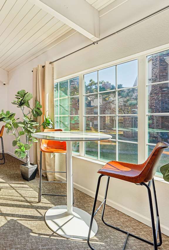 A living room with a white couch, a coffee table, and a large window with blinds.