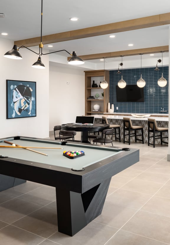 a clubhouse with a pool table and a bar with a tv