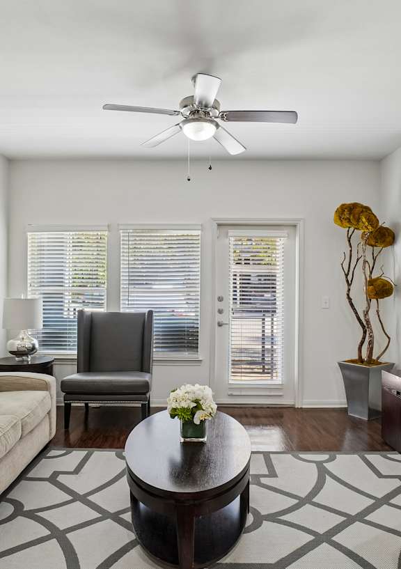 A living room with a beige couch, a coffee table, and a ceiling fan.
