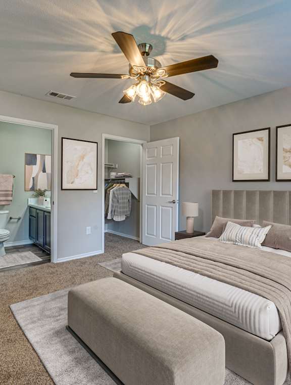 A bedroom with a large bed and a ceiling fan.