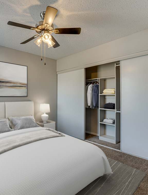 A bedroom with a large bed and a ceiling fan.