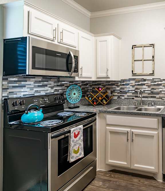 A modern kitchen with a black stove top and white cabinets.