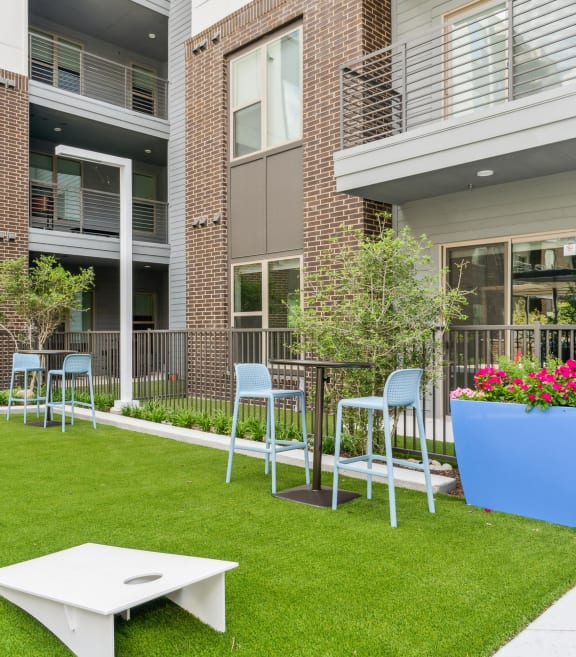 a yard with a table and chairs in front of an apartment building