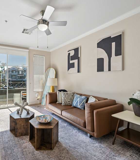 A living room with a white couch and a colorful wall hanging.