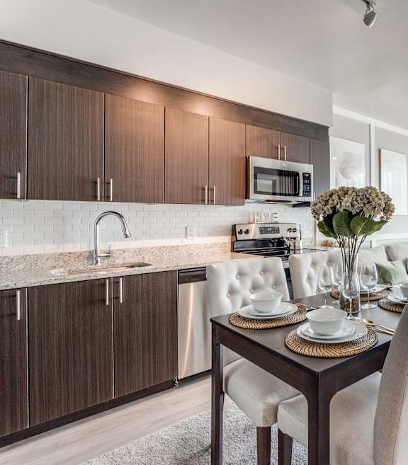 A modern kitchen with a dining table set for two.