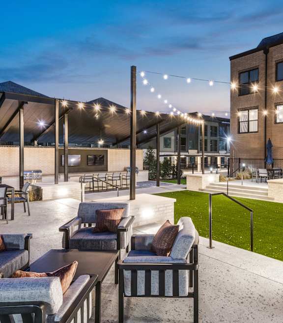 A patio with outdoor furniture and string lights.