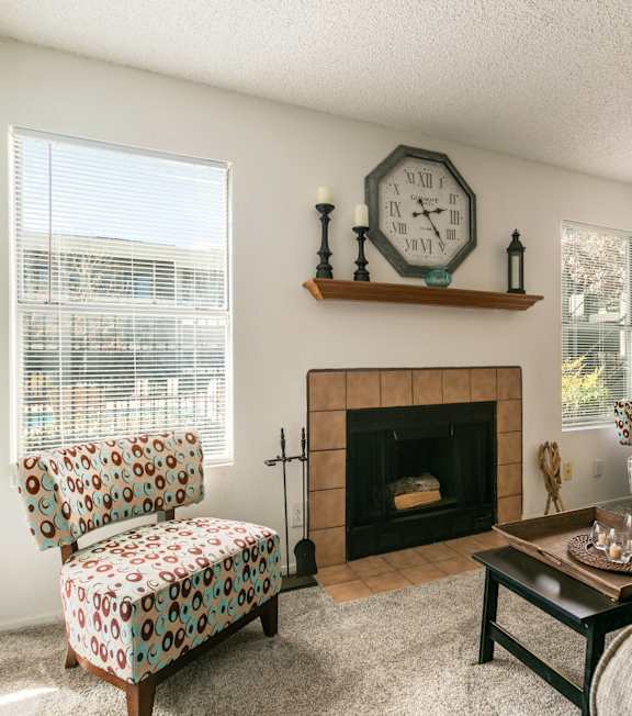 A living room with a fireplace, two chairs, and a clock on the wall.
